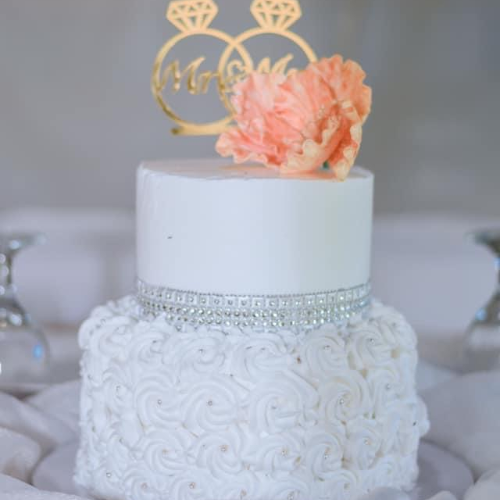 Zweistöckige Torte mit gespritzten Blumen und einen Torten Toper.