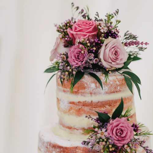 Zweistöckige Torte. Der Stil ist Naked Cake und vielen frischen Blumen