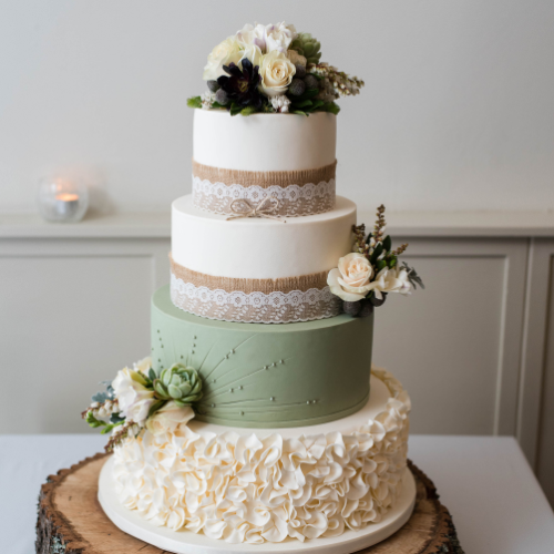 Vierstöckige Torte mit Blumenelementen. Die Farben der Torte sind grün und weiß