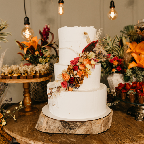 Dreistöckige Torte mit Trockenblumen als Dekoration auf einer Baumscheibe.